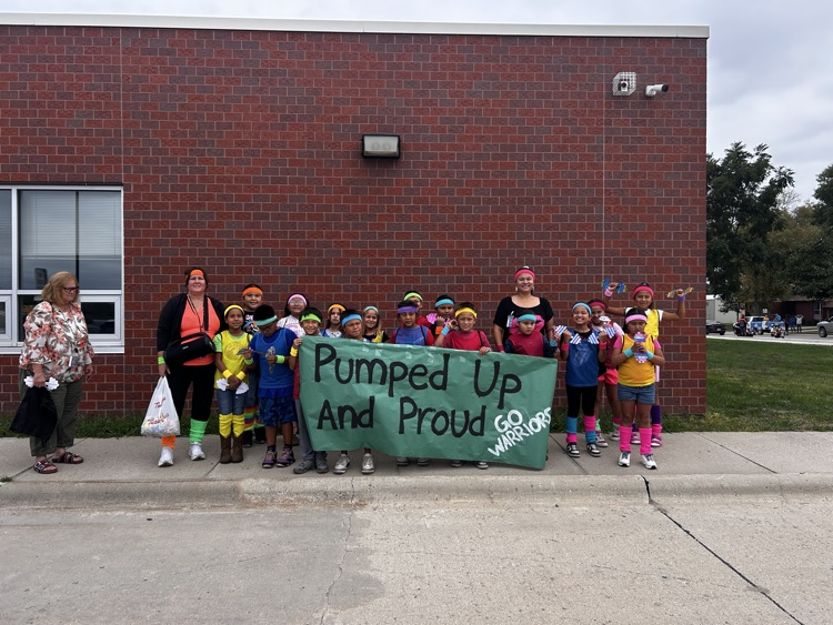 large group of elementary students with neon work out gear on holding a green sign 