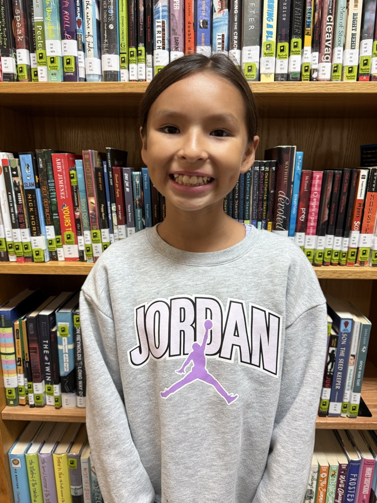 Fifth-grade student smiling in a school library.