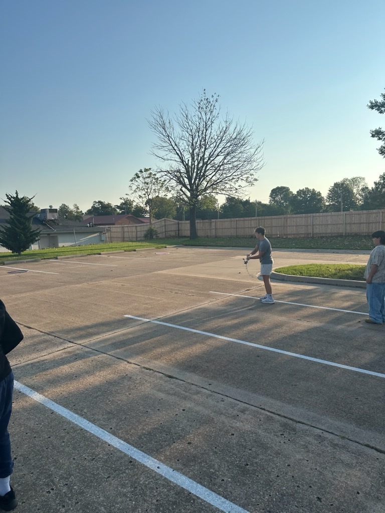 student outside practing casting a fishing line