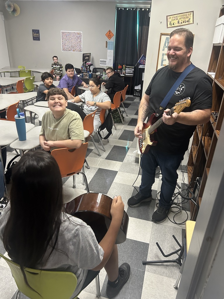 students listening to teacher play guitar