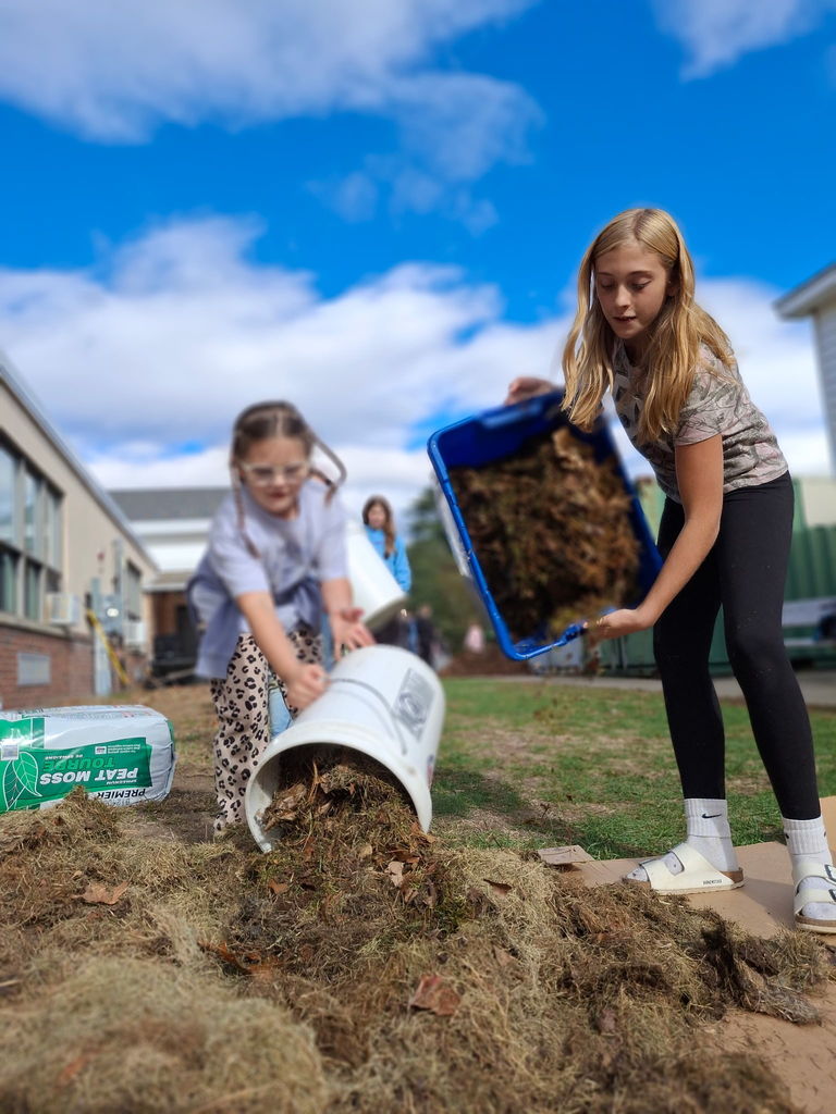 Two students working together to pour soil.