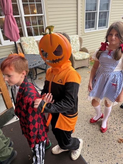 A child in a pumpkin costume walking into Poplin.