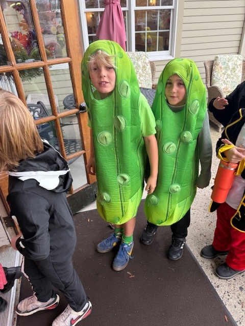 Two students in pickle costumes walking into Poplin.