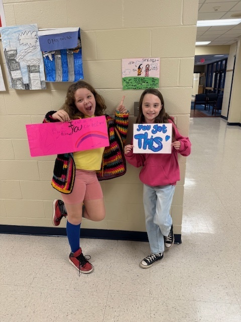 Two students posing with their encouraging posters.