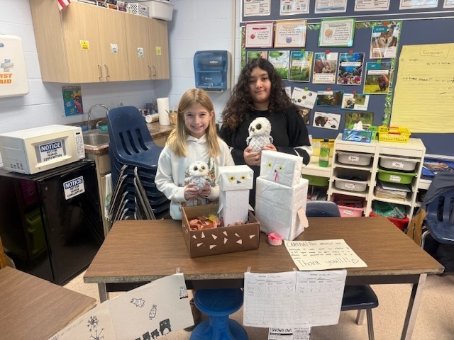 Two students posing with their snowy owl volume zoo projects!