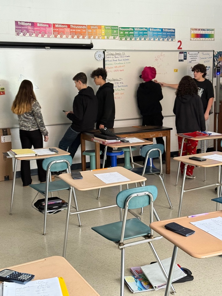 Students problem-solving on vertical dry erase surfaces.