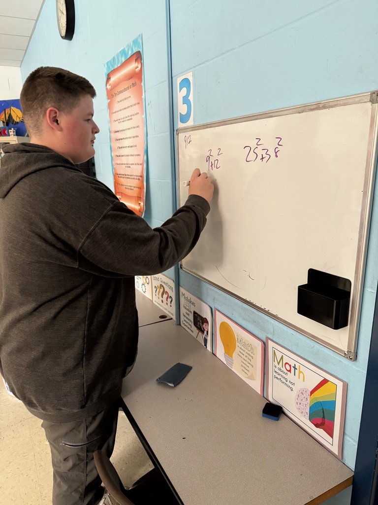 Students problem-solving on vertical dry erase surfaces.