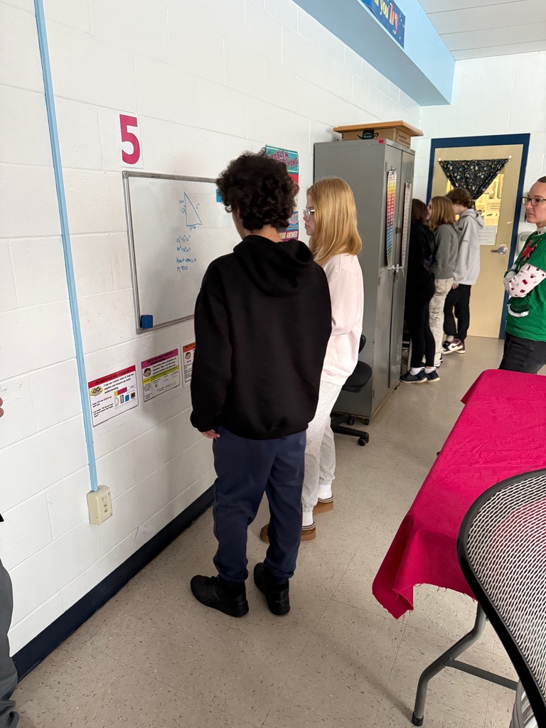 Students problem-solving on vertical dry erase surfaces.