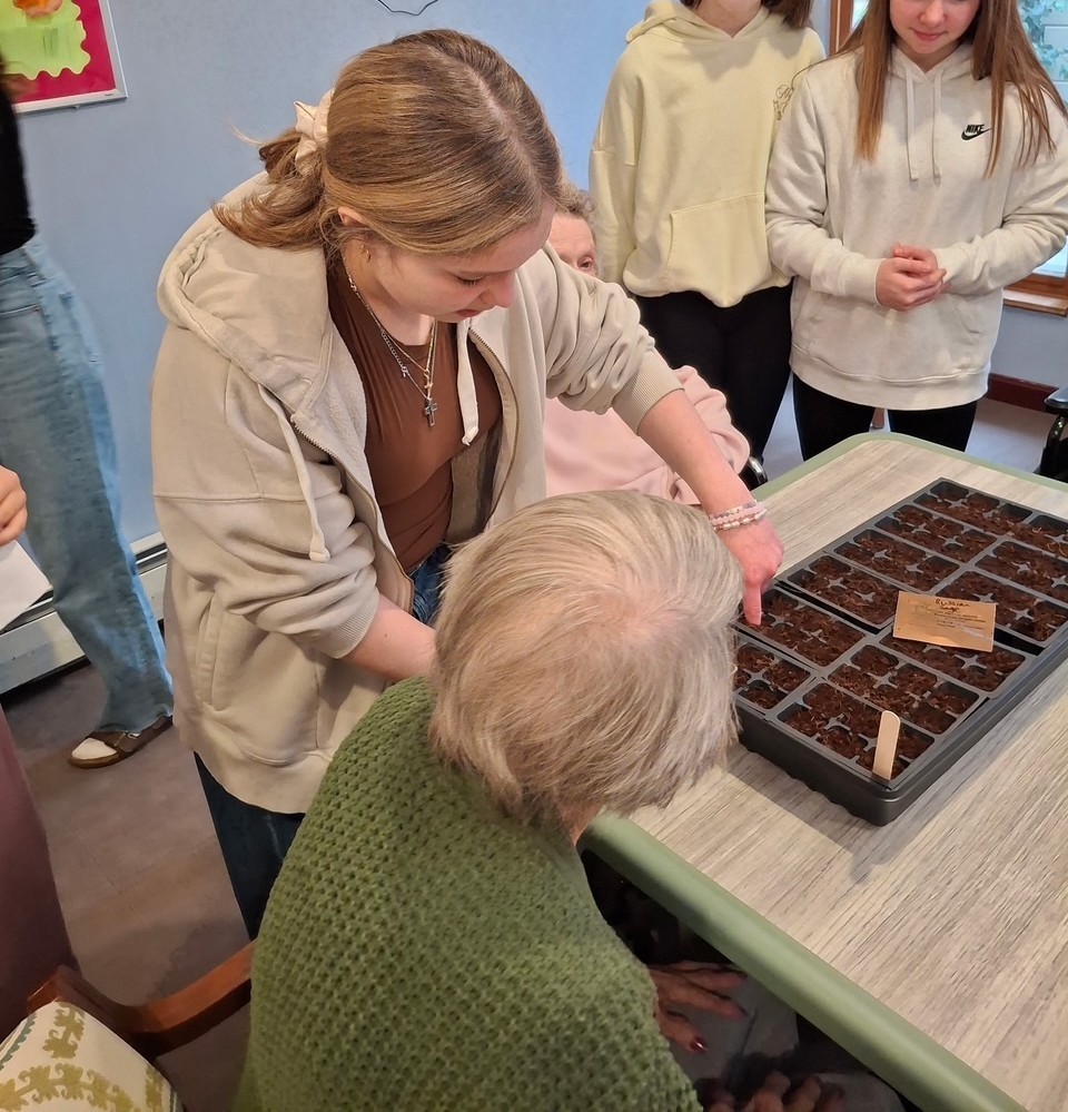Student planting seeds with a Poplin resident