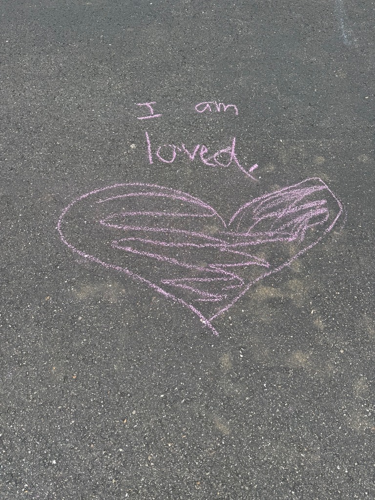 A student chalk message: "I am loved."