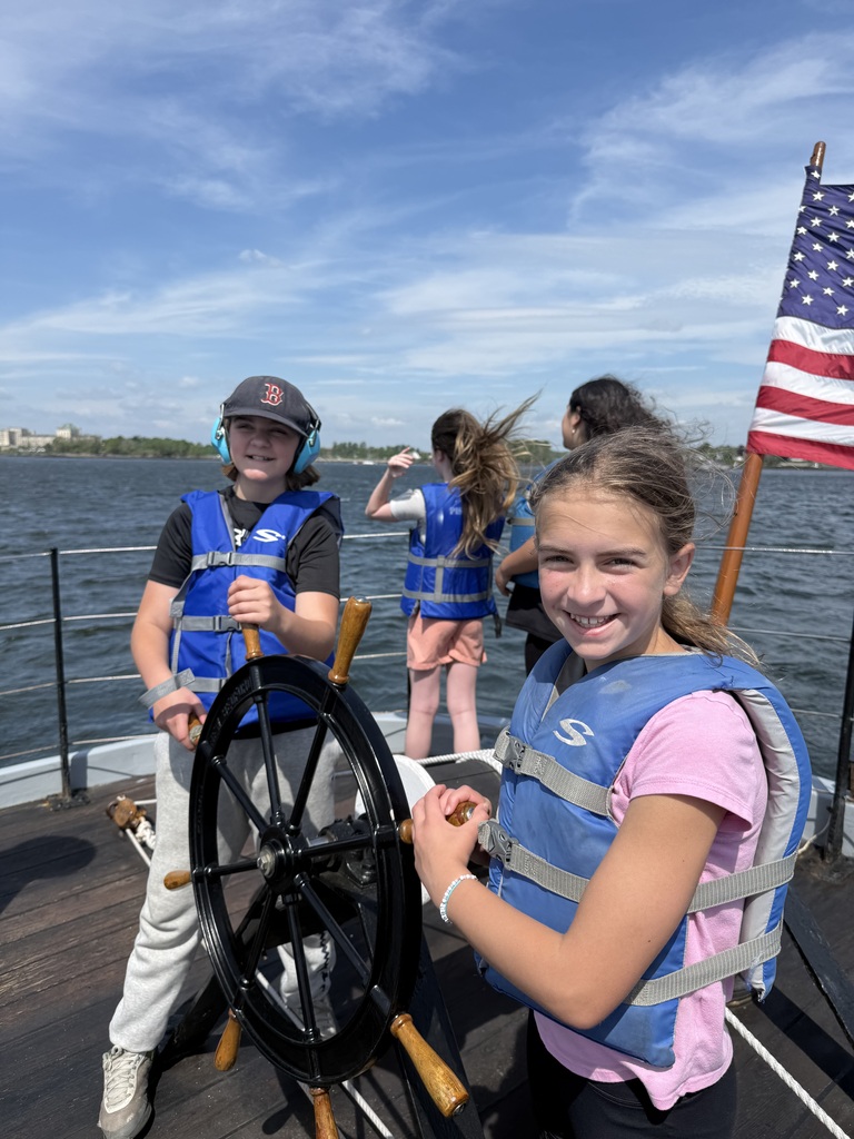 Students smiling as they steer the boat.