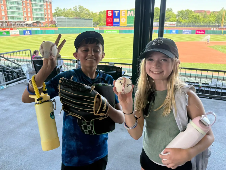Students smiling with signed baseballs at the Fisher Cats game