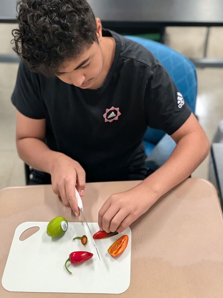 A student cutting up peppers for salsa