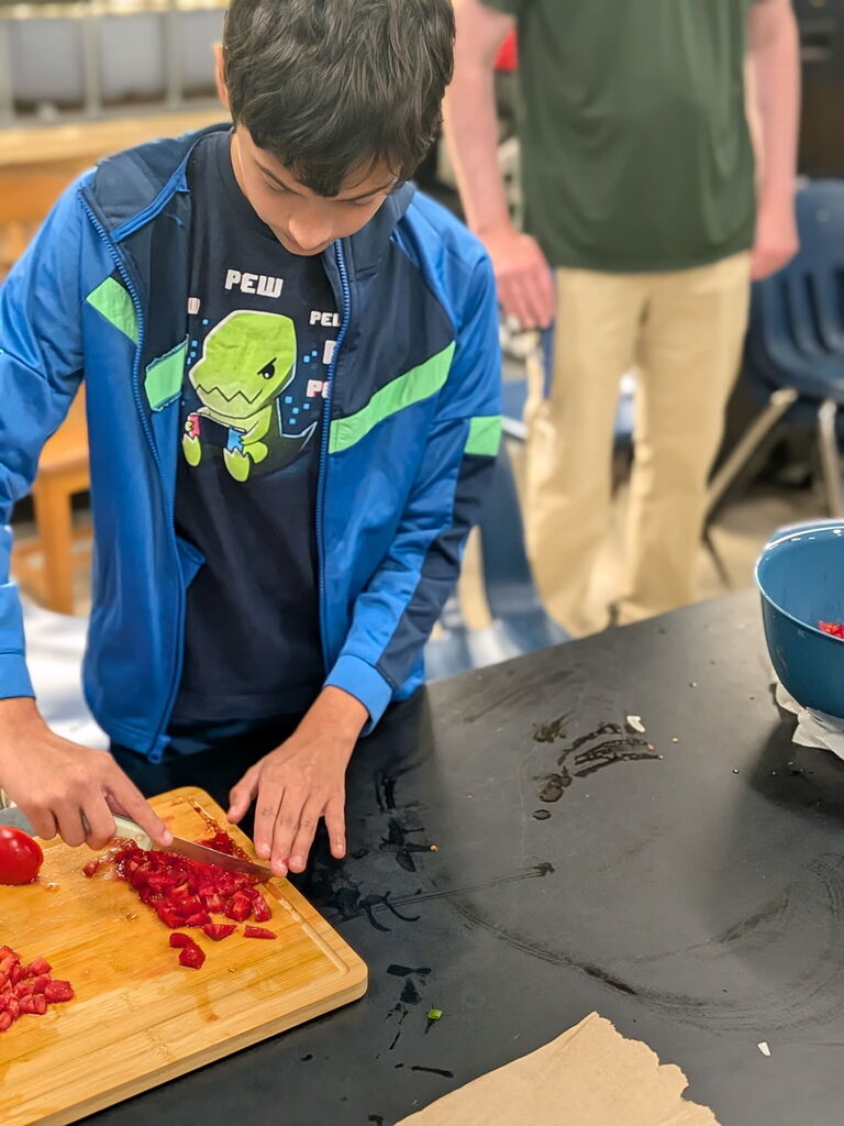 A student cutting up tomatoes for salsa