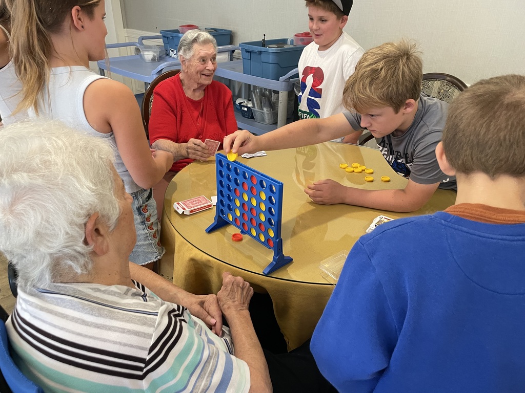 Fifth graders playing Connect 4 with residents