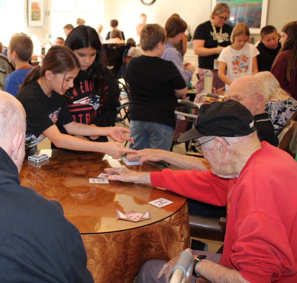 Fifth graders playing cards with residents