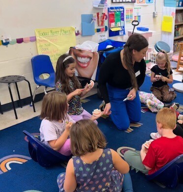 Mrs. Therrien teaching students how to brush their teeth