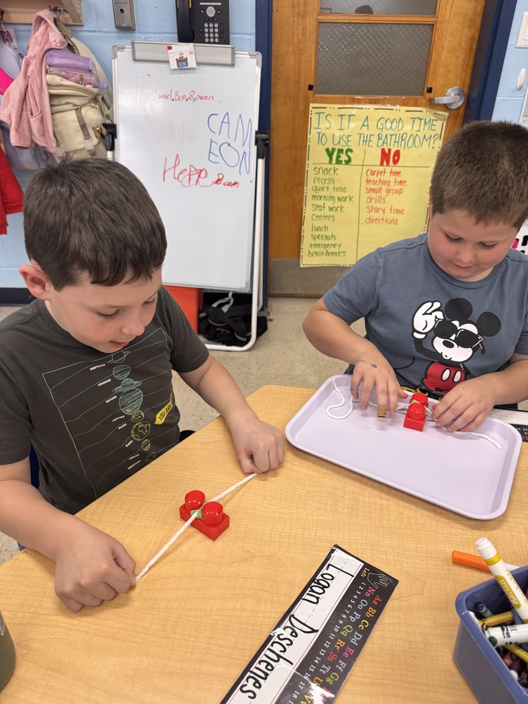 Two students practicing flossing play doh out of duplo blocks, or teeth!