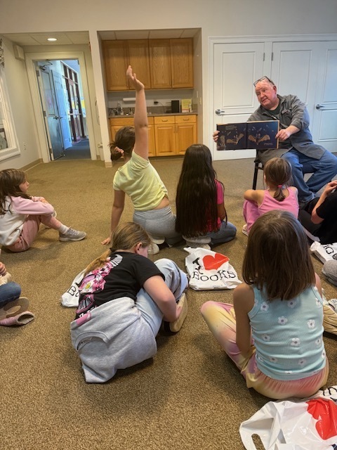 Students listening to Mr. Eric read a story.