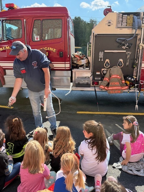 John Roderick showing students what a burnt electrical cable looks like, a fire hazard.
