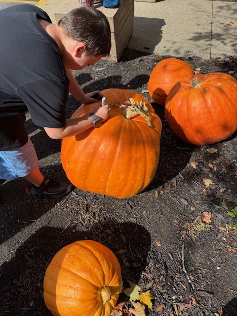A student signing a giant pumpkin