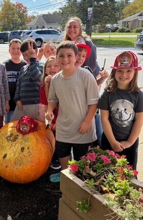 Students posing with one of the giant pumpkins
