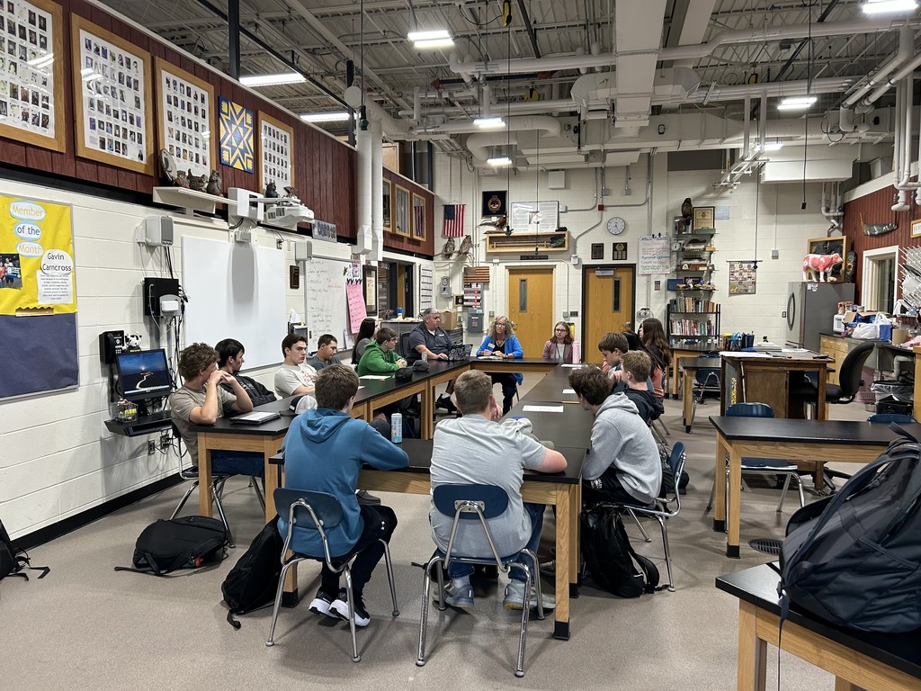 A class of studnets sitting in a circle talking with the represnentitive 