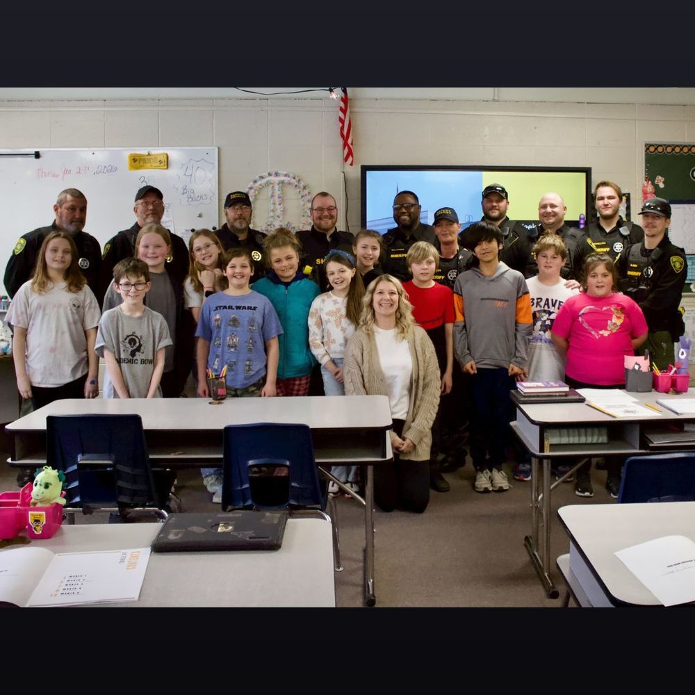5th grade class of students pose for a picture with 10 uniformed sheriff's deputies 