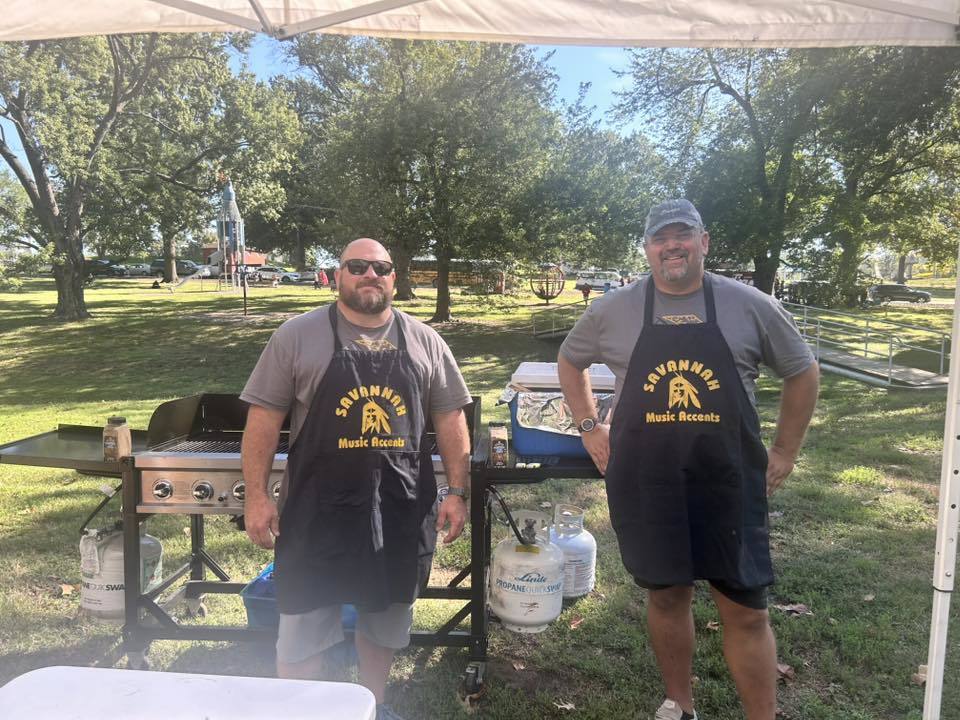 Mat Eiman and Mr. Fulton stand in front of grills wearing aprons that read, "Savannah Music Accents"