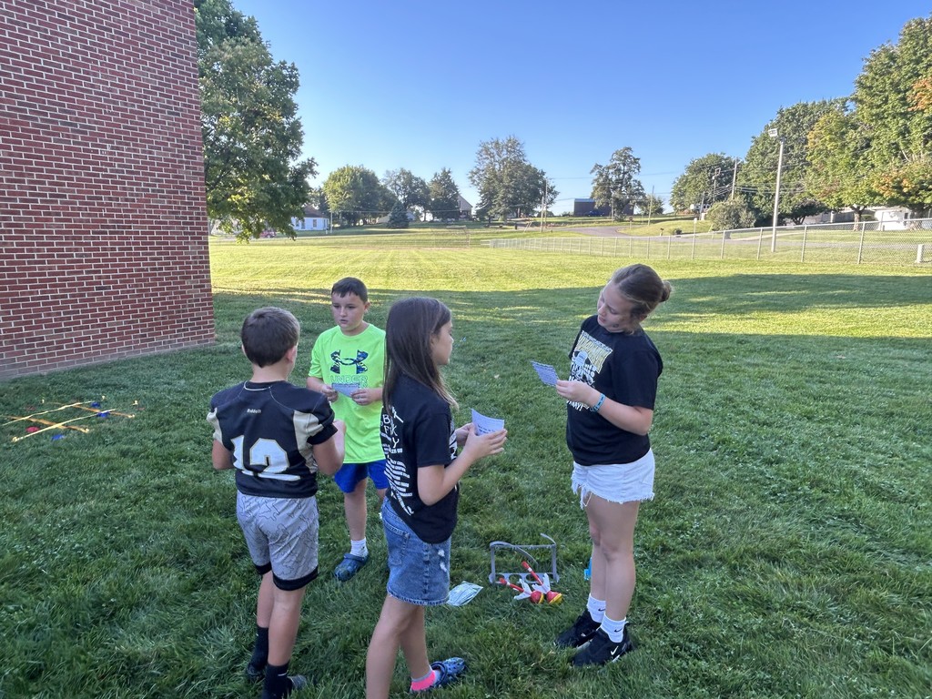IMG_2665Four students gather around a small ladder-toss game set on the grass.