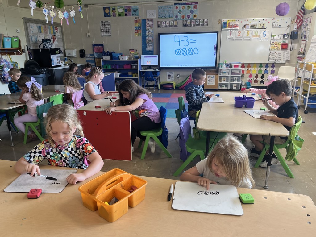 Classroom full of kindergarteners using personal white boards to practice math skills. 