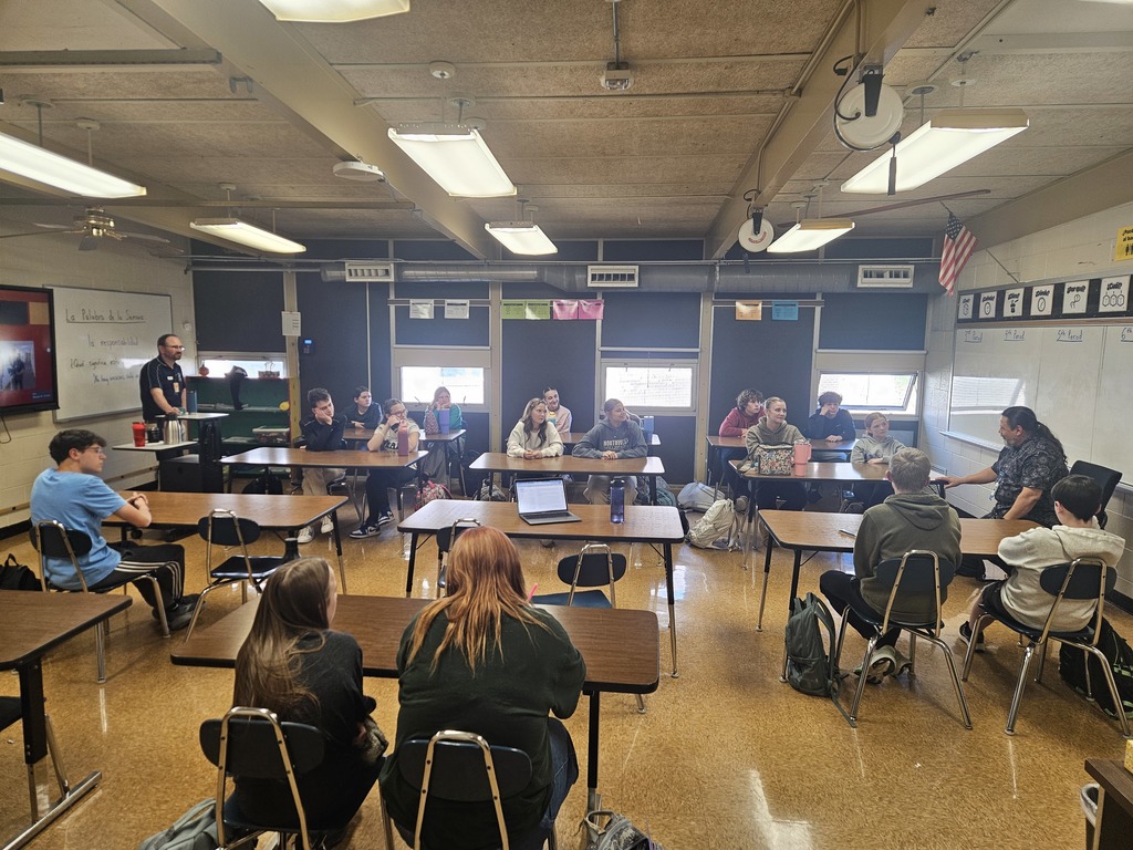 A wide shot of the classroom showing students listening to two guest speakers discussing careers related to Spanish language and healthcare.