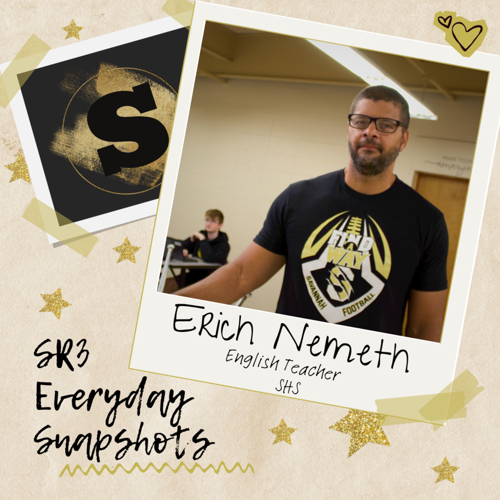 “English teacher Erich Nemeth stands in a Savannah High School classroom wearing a black Savannah football shirt, with a student seated at a desk in the background.”