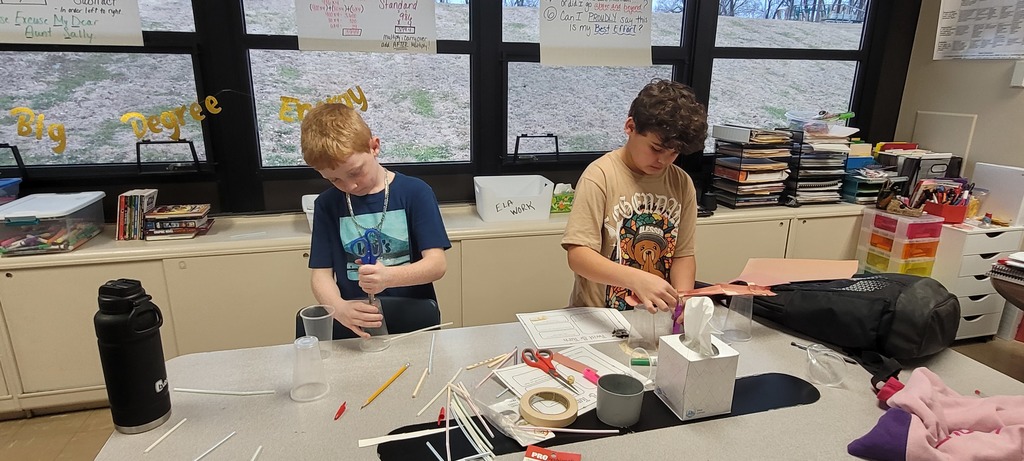 Two students construct models using cups, paper, and straws during science club.