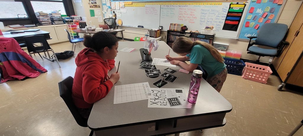 Two students work together on a fraction activity at a classroom table.