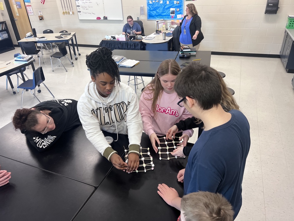 Students examine and adjust marshmallow-and-toothpick models representing atoms and bonds.