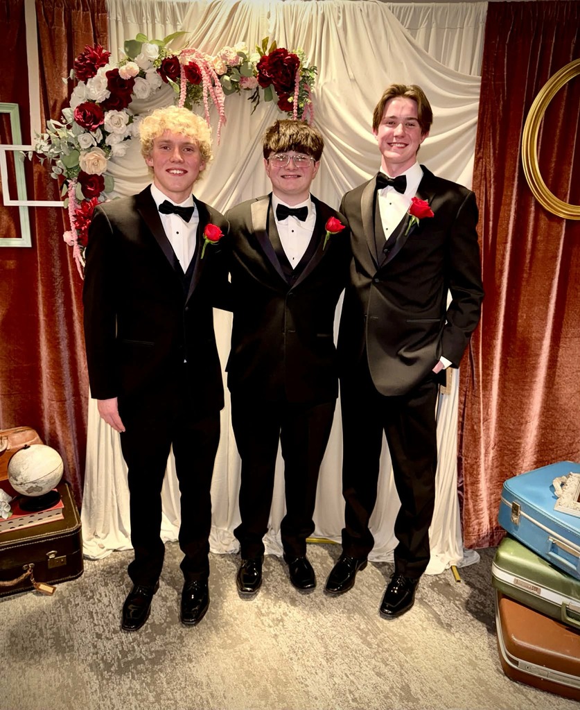 Three SHS seniors in black tuxedos with red boutonnieres pose at the Cotillion for Achievement.