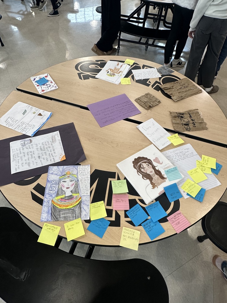 Student projects about Ancient Egypt displayed on a cafeteria table, including drawings, notes, and artifact replicas.