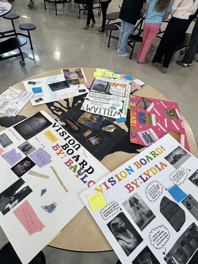 Tables filled with student vision boards and projects about Ancient Egypt during a classroom gallery walk.