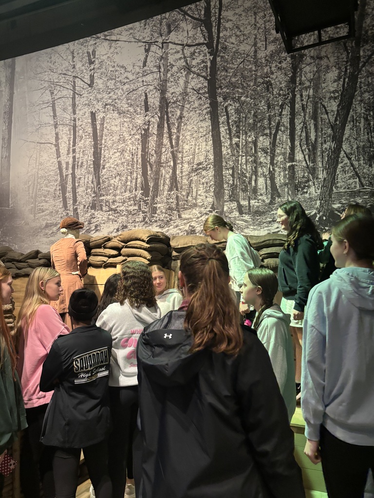 Students stand around a World War I trench exhibit with sandbags and a black-and-white forest backdrop at the National WWI Museum and Memorial.