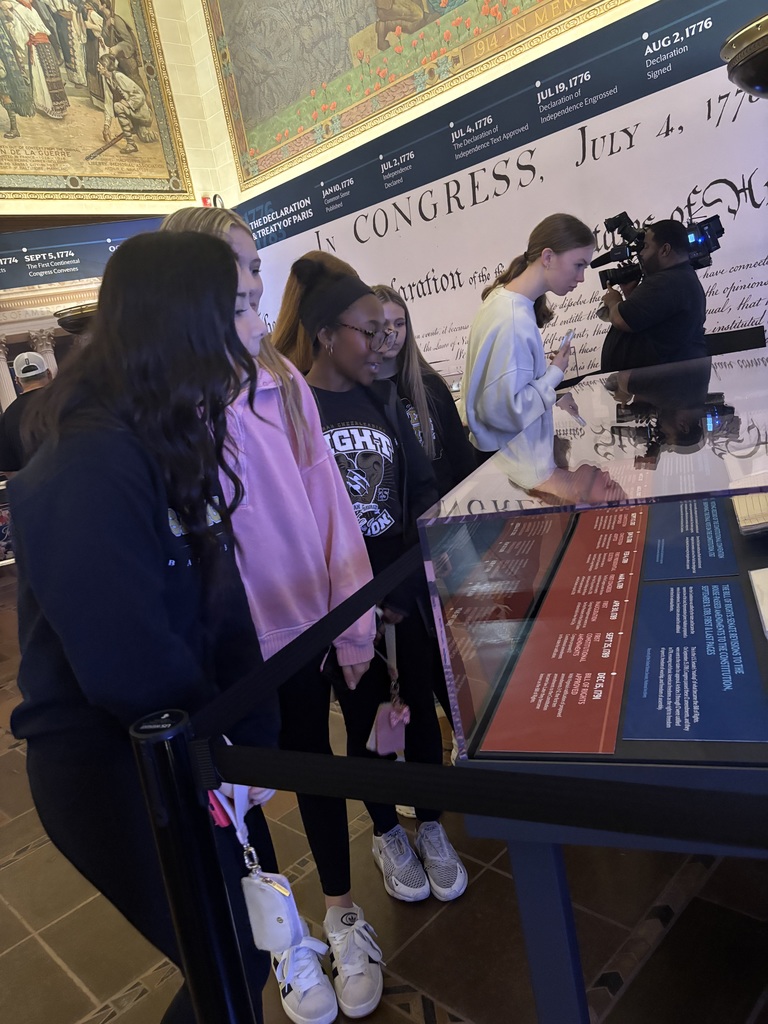 Students view a display case in front of a large Declaration of Independence wall graphic during a museum visit.