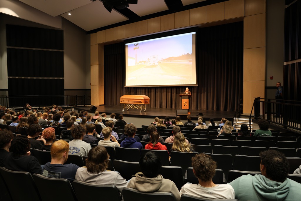 Students watch a presentation on stage with a casket displayed during the Docudrama event at Savannah High School.