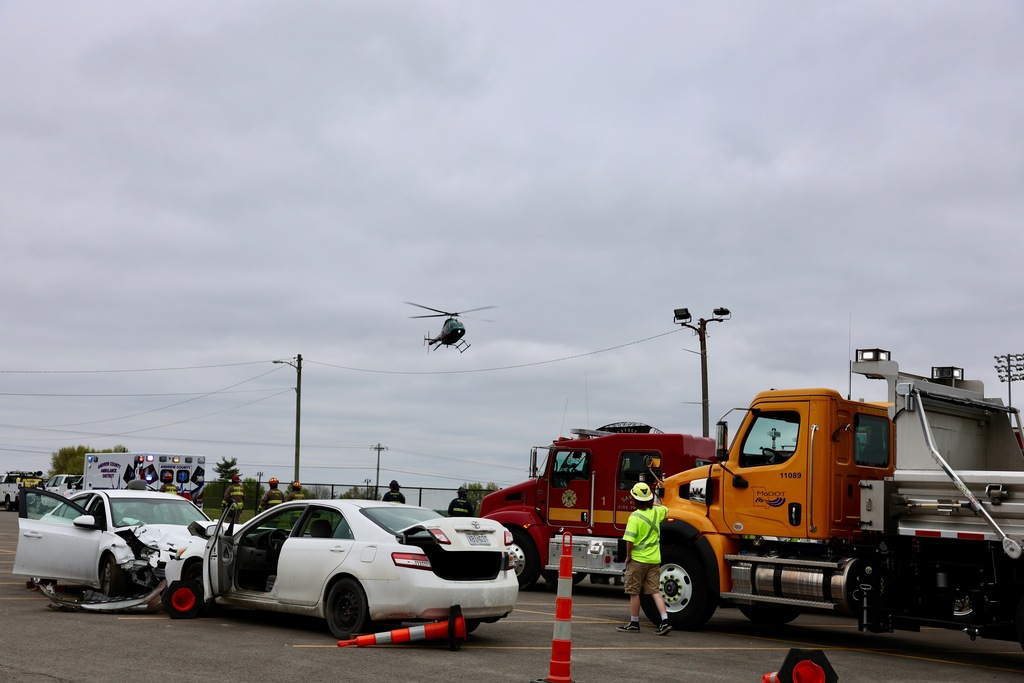 Staged crash scene with damaged cars, fire truck, and emergency responders during the Docudrama simulation.