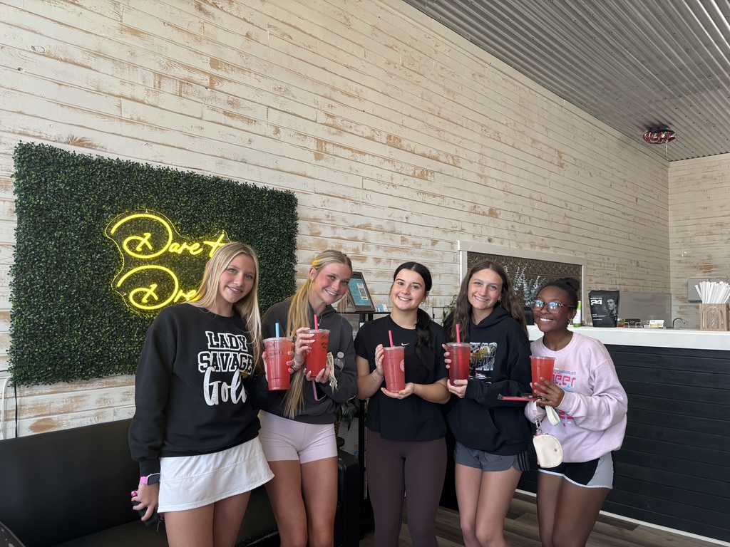 Five students smile and hold drinks inside Savage Nutrition during their stop on the Savannah square.