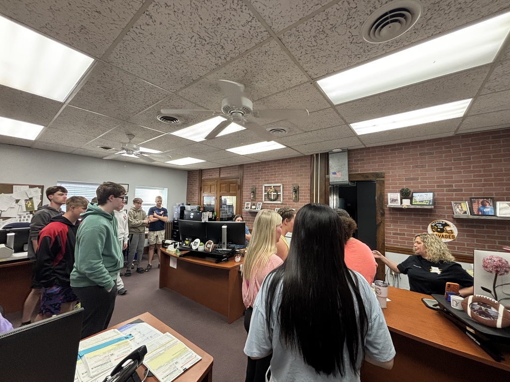 Students stand inside a county office and listen as a staff member explains how local government work is handled.