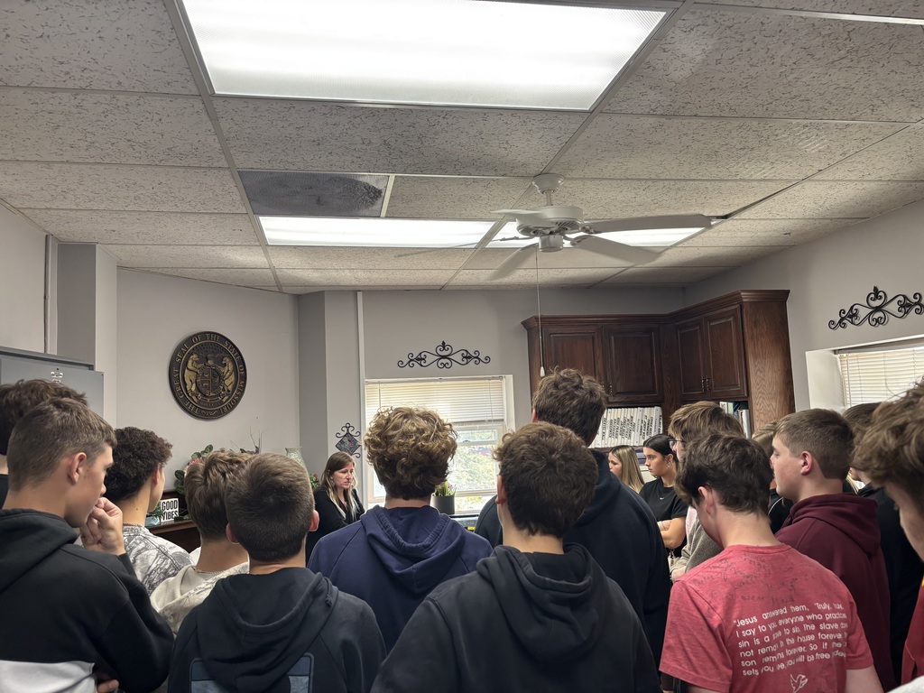Students stand inside a county office and listen as a staff member explains how local government work is handled.