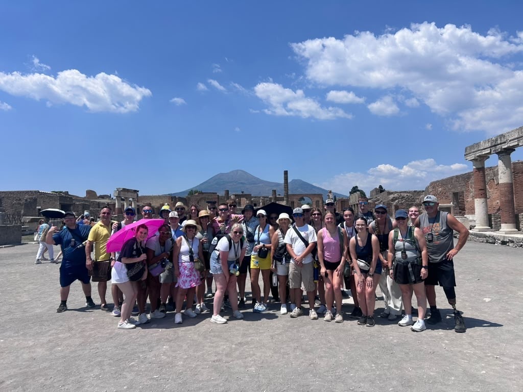 Savannah High School students pose at Pompeii with Mount Vesuvius in the background on a bright, sunny day.