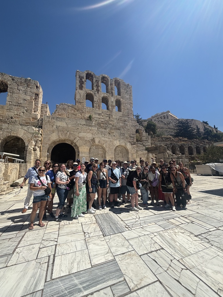 A group of Savannah High School students and chaperones pose at an ancient stone amphitheater in Greece.