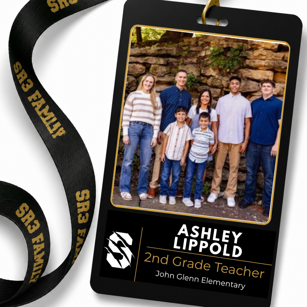 Black SR3 staff ID badge hanging from a black "SR3 Family" lanyard on a white background. The badge features a portrait of Ashley Lippold. Text identifies her as a 2nd Grade Teacher at John Glenn Elementary.