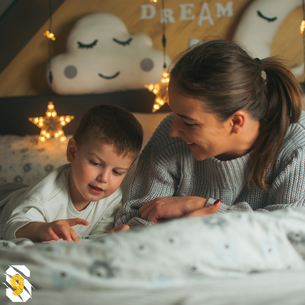 Parent and young child relaxing together at bedtime, representing the transition back to school-year sleep routines.